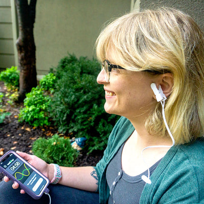 Person using Vitality Smartcable ear-clip device during a 5-minute daily wellness session